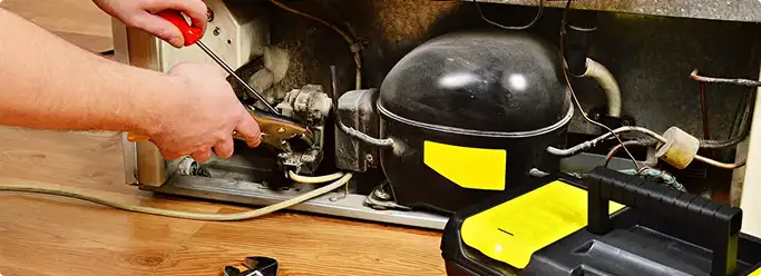Refrigerator repair technician fixing the compressor and wiring in Roscoe, IL