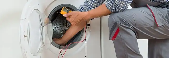 Dryer repair technician inspecting and repairing a clothes dryer in Rockford, IL