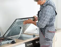 Appliance repair technician installing a built-in cooktop in Rockford, IL