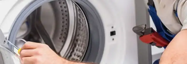 Appliance technician repairing a clothes dryer drum and internal parts in Rockford, IL