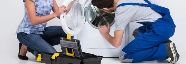 Washer repair technician inspecting a front-load washing machine with tools in Rockford, IL