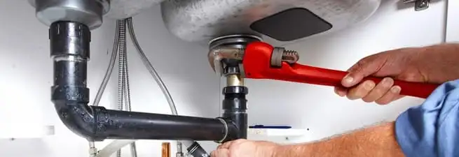 Garbage disposal repair technician tightening the sink drain and disposal connection in Rockford, IL