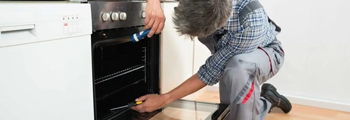 Oven repair technician inspecting and servicing an electric oven in Rockford, IL