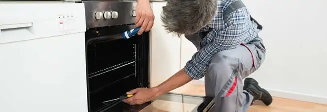 Oven repair technician inspecting and servicing an electric oven in Rockford, IL