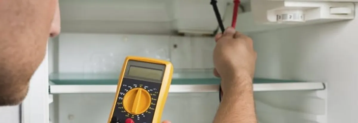 Refrigerator repair technician testing electrical components with a multimeter in Rockford, IL