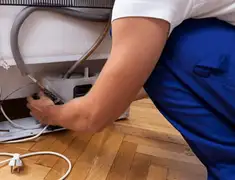 Appliance repair technician fixing refrigerator water line and connections in Rockford, IL