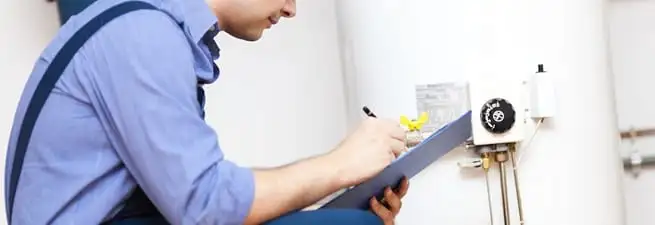 Water heater repair technician inspecting the unit and recording service notes in Rockford, IL