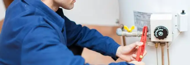 Water heater repair technician adjusting the temperature control and gas valve in Rockford, IL